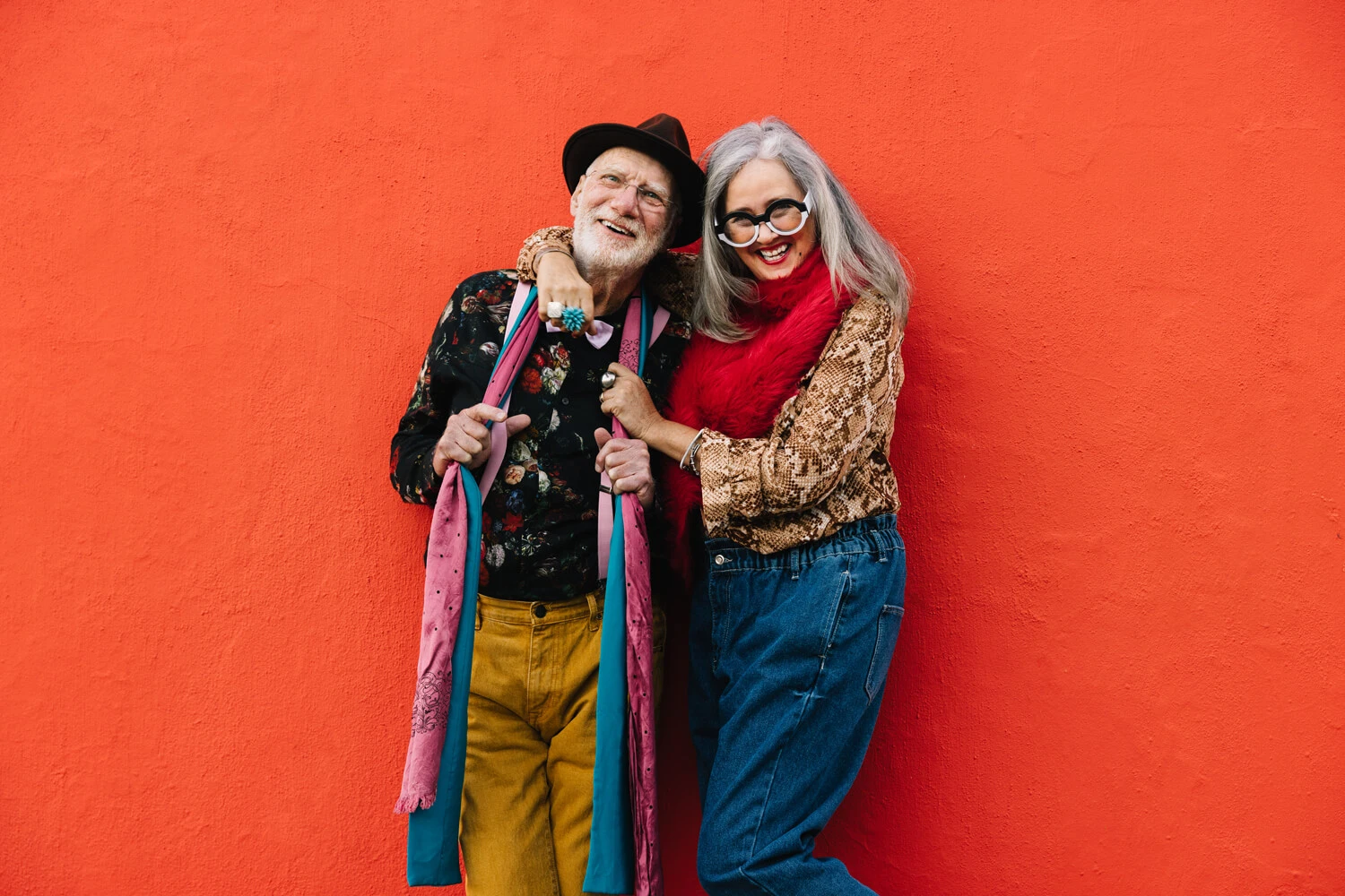Two mature people against an orange wall